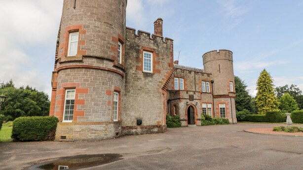 A historic castle with a large courtyard, stone walls, and a prominent round tower. - Rob Roy Apartment (Glasgow)