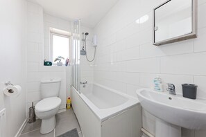 A bathroom with a toilet, shower, and sink.