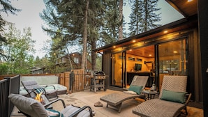A patio with outdoor furniture, a fire pit, and a view of the forest.