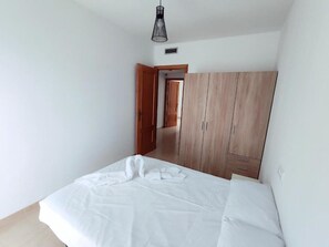 A bedroom with a bed, wooden wardrobe, and a hanging light fixture. - Costa Norte Vinaros (Vinaròs)