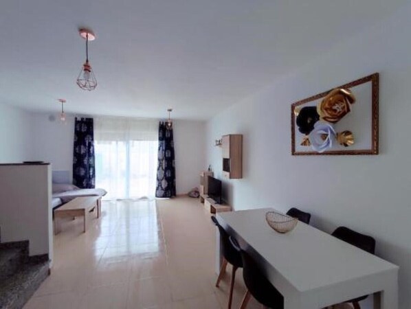 A modern living room with a dining area, a sofa, a TV, and a painting on the wall. - Costa Norte Vinaros (Vinaròs)