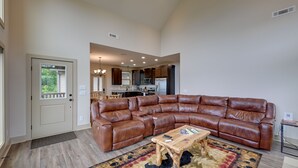 Ein geräumiges Wohnzimmer mit einem großen, ledernen Ecksofa, einem Couchtisch und einem gemusterten Teppich.