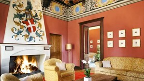 A room with a fireplace, floral-patterned sofas, and framed pictures on the wall. - Villa Soleil  (Colleretto Giacosa)