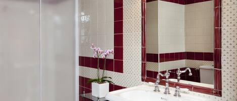 A bathroom with a white sink, a mirror, and a shower.