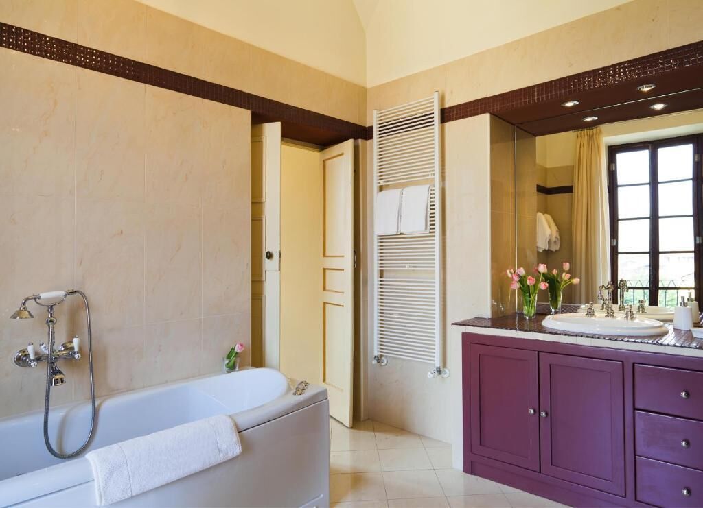 Un baño con bañera, tocador con lavamanos y un espejo grande.