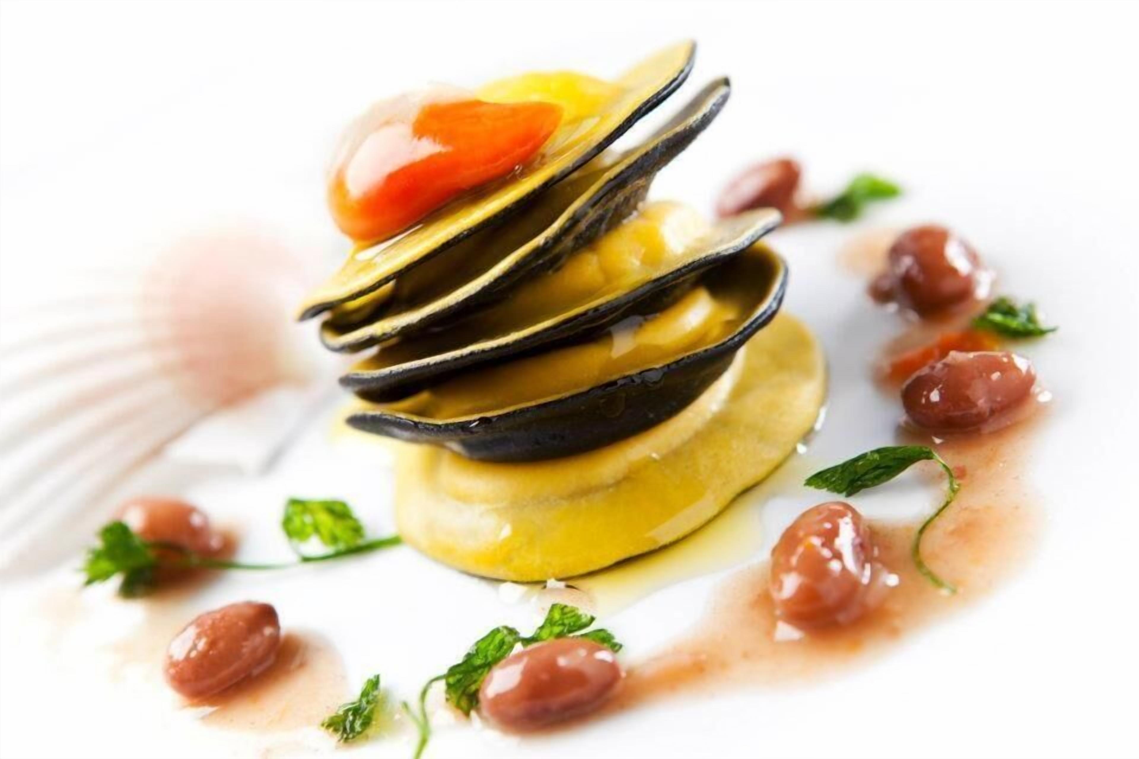 A seafood dish with mussels, cherry tomatoes, and herbs on a white plate.