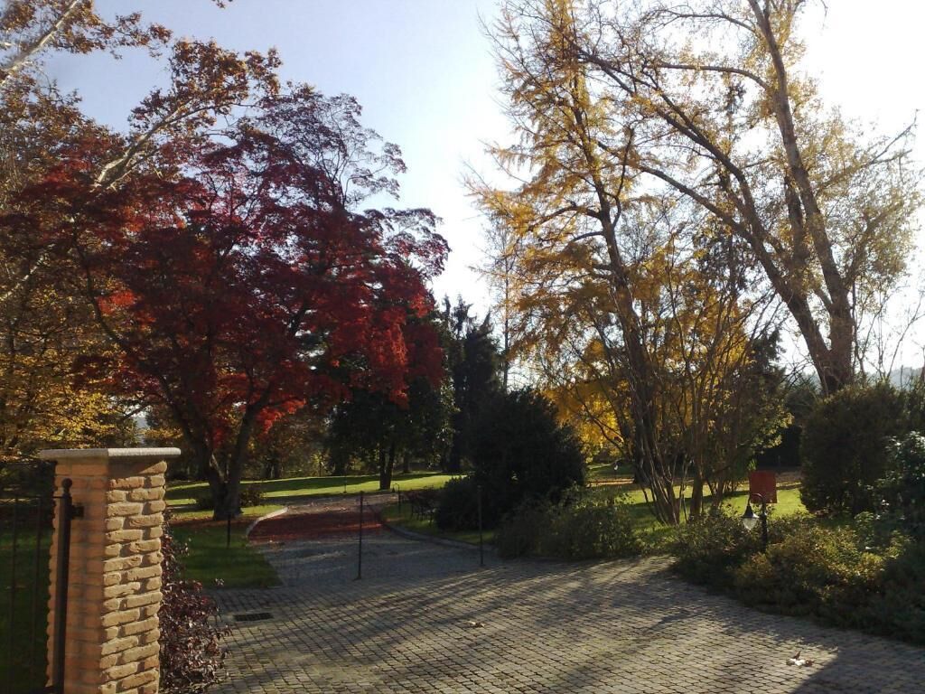 A paved driveway leading to a brick building with a stone pillar.