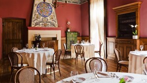 A dining area with round tables, chairs, and a fireplace. - Villa Soleil  (Colleretto Giacosa)