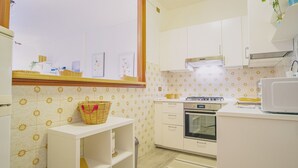 A kitchen with white cabinets, a stove, an oven, and a microwave.