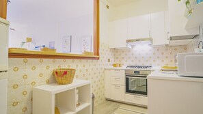 A kitchen with white cabinets, a stove, an oven, and a microwave.
