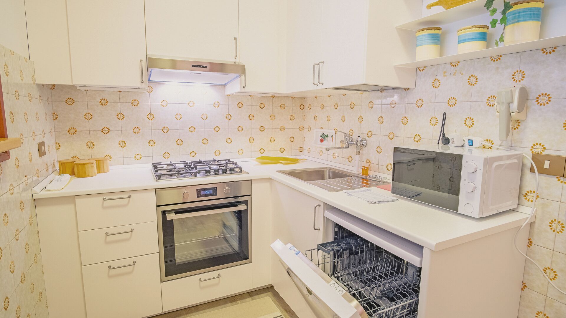 Une cuisine compacte équipée d’une cuisinière, d’un four, d’un four à micro-ondes et d’un lave-vaisselle.