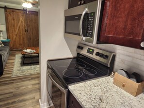 A kitchen with a stainless steel stove, a microwave, and a wooden cabinet.