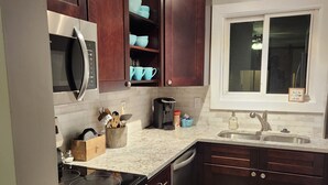 Una cucina moderna con mobili in legno scuro, elettrodomestici in acciaio inossidabile e una finestra sopra il lavello.