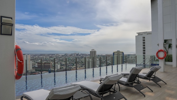 A rooftop infinity pool with lounge chairs, a city view, and a lifebuoy. - Citadines Benavidez Makati (Makati)
