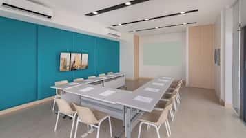 Sala de conferências com uma longa mesa, cadeiras, tela de projetor e uma parede de destaque em tom verde-água.
