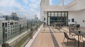 A modern rooftop terrace with glass railings, outdoor seating, and a city view. - Citadines Benavidez Makati (Makati)