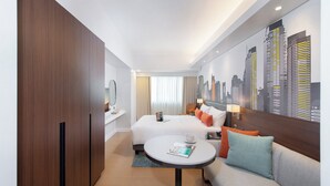 A hotel room with a bed, a sofa, a small table, a cityscape mural, and a wooden wardrobe. - Citadines Benavidez Makati (Makati)