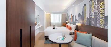 Habitación de hotel con cama, sofá, una mesita, un mural con vista a la ciudad y un armario de madera.