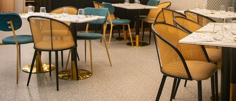 A modern restaurant interior with tables and chairs, a bar area, and a large screen displaying the restaurant's name.