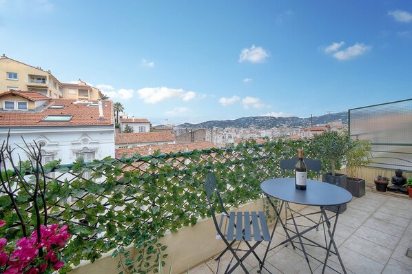 A terrace with a table and chairs, a bottle of wine, and potted plants. - STUDIO LUMINEUX 200 m DES PLAGES A0B192 (Cannes)