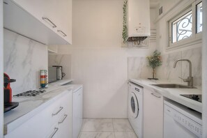 A compact kitchen with a washing machine, a sink, and a window with decorative ironwork. - STUDIO LUMINEUX 200 m DES PLAGES A0B192 (Cannes)