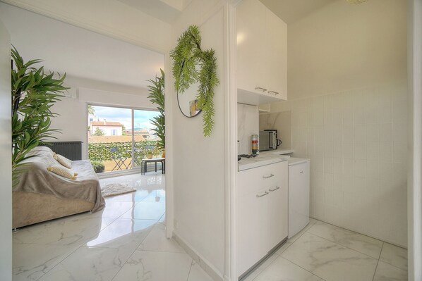 A modern kitchen with white cabinets, a coffee maker, and a view to the outside. - STUDIO LUMINEUX 200 m DES PLAGES A0B192 (Cannes)