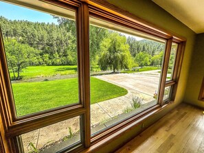 A room with large windows offering a view of a green landscape with trees and a curved driveway.