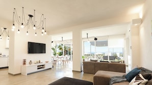 A spacious living area with a modern chandelier, a flat-screen TV, and a comfortable seating arrangement. - Villa Marsala - Five Bedroom Villa, Sleeps 12 (Marsala)