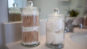 Deux bocaux en verre, munis de couvercles, sont posés sur un comptoir : l’un est rempli de cotons-tiges blancs et l’autre de cotons-tiges bruns.