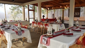 A restaurant with multiple tables set for dining, featuring white tablecloths and red accents.