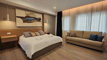 A modern bedroom with a large bed, a sofa, and a painting on the wall.