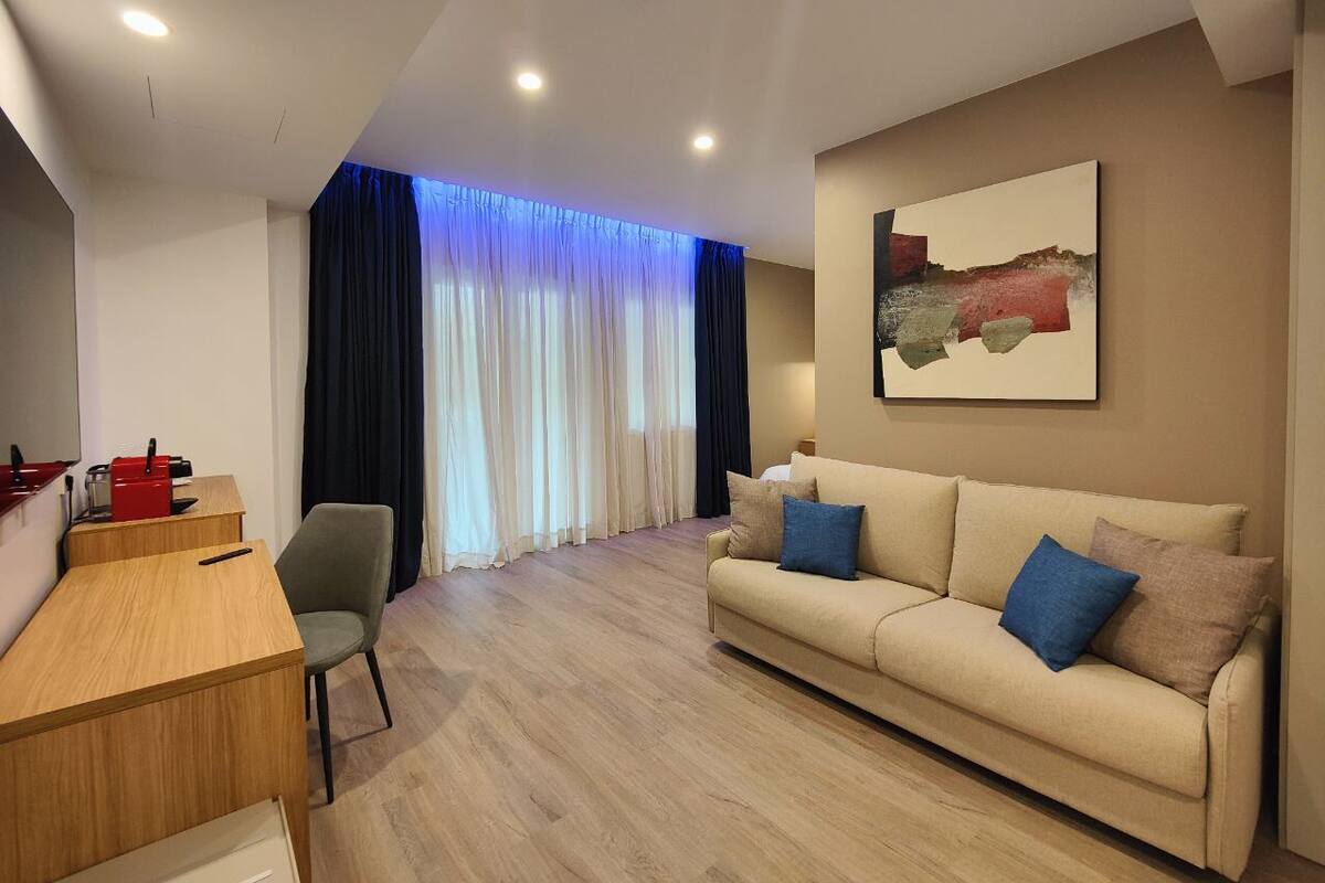 A modern living room with a sofa, a dining table, and a painting on the wall.