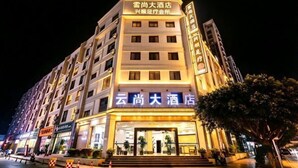 A multi-story hotel with illuminated signage, a prominent entrance, and a tree in the foreground.