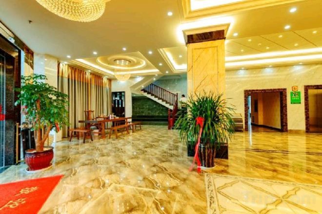 A hotel lobby with a marble floor, a staircase, and potted plants.