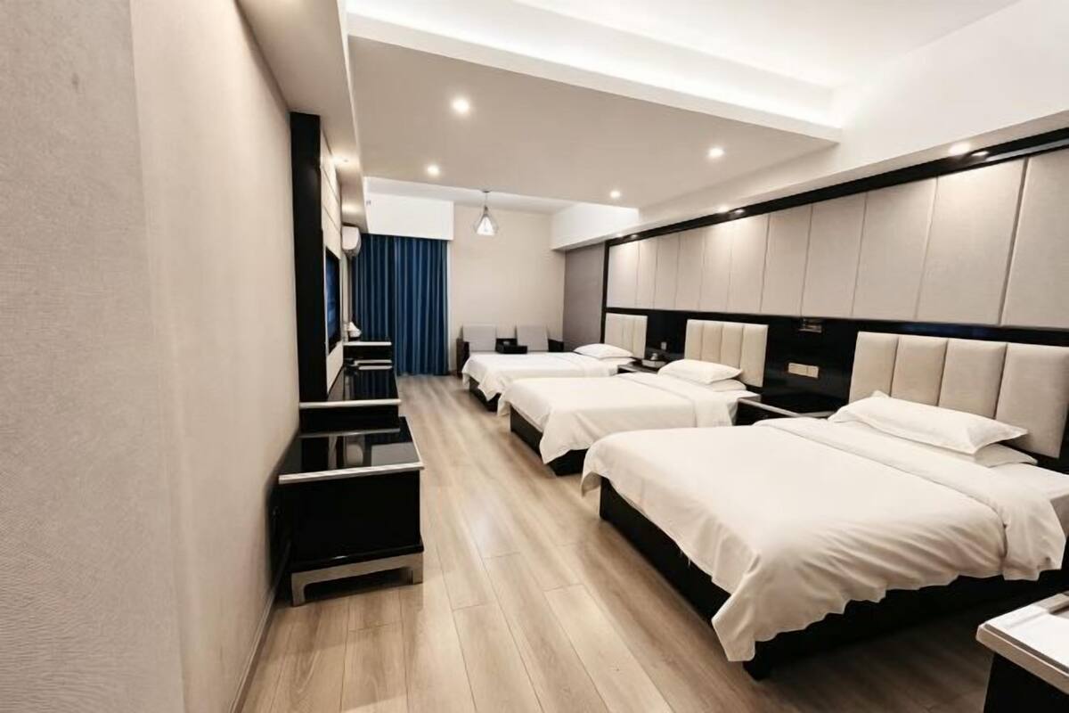 A hotel room with three beds, a desk, and a staircase.