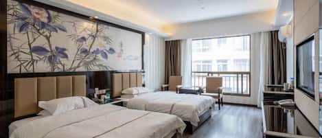 A hotel room with two beds, a TV, a desk, and a large window.
