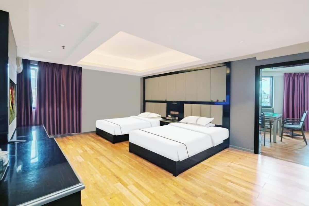 A hotel room with two beds, a desk, and a view of the outside.