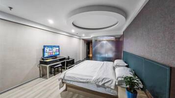 Habitación de hotel moderna con una cama, un escritorio con computadora y televisión.