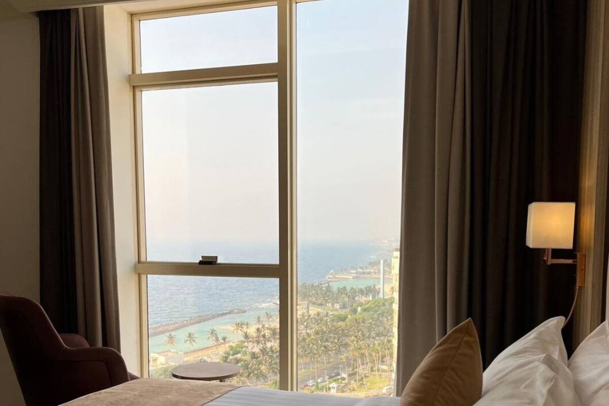 A hotel room with a large window offering a view of the ocean and a resort.