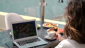 A person using a MacBook Air at a table with a meal and a cup of coffee. - Seafront Luxury Suites Jeddah Corniche (Jeddah)