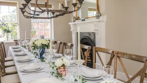 A long dining table set for a formal meal with white plates, glasses, and a centerpiece of white flowers. - The Admiral's Home (Whitehaven)