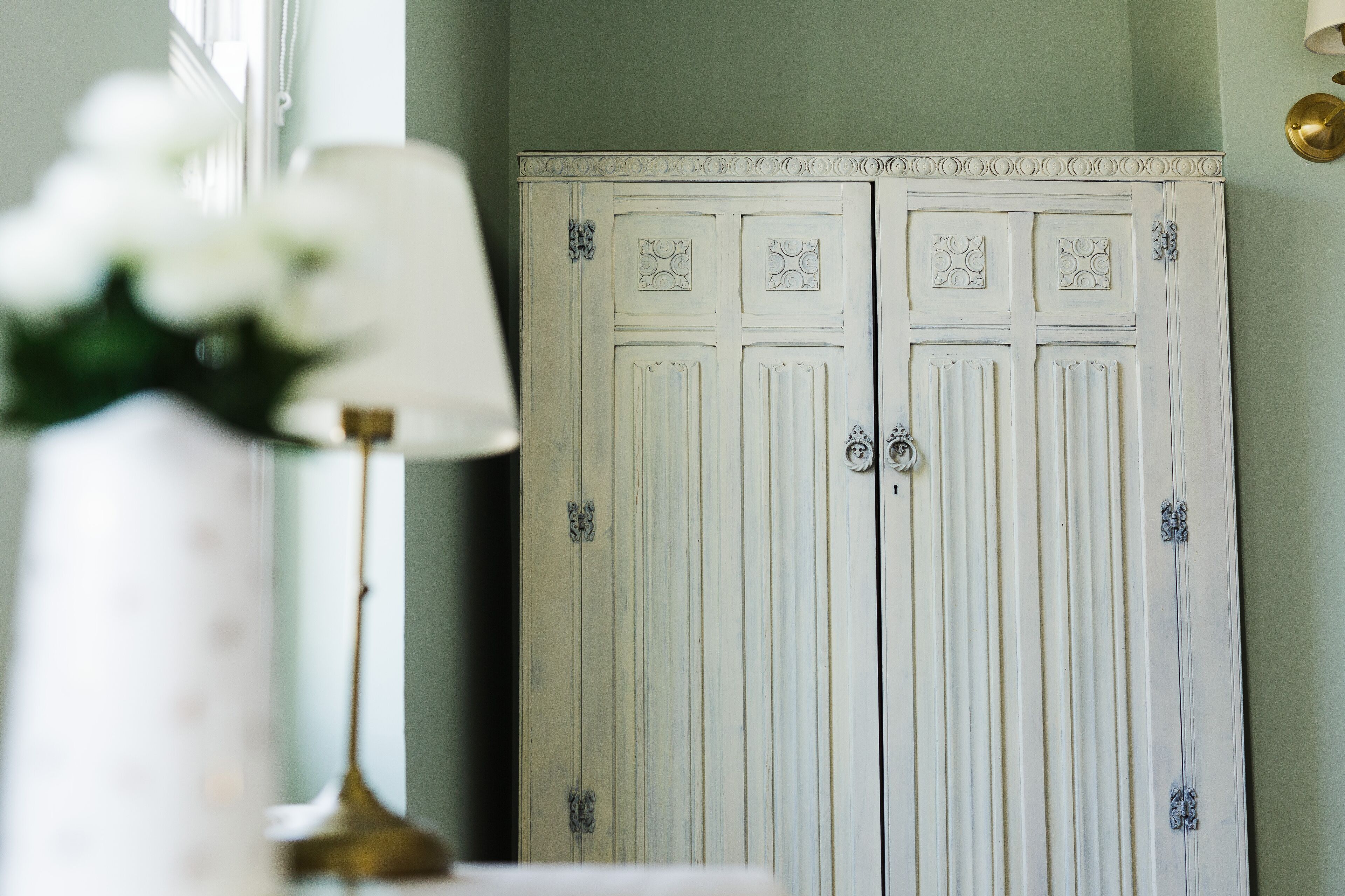 Une pièce avec une armoire blanche ornée de panneaux décoratifs et dotée d’une poignée en laiton.