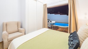 A bedroom with a bed, a chair, and a view of a swimming pool at night. - Cubo's Finca La Graciosa / private pool / free wifi (Alhaurin de la Torre)