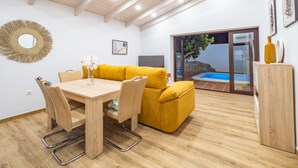 A modern interior with a wooden dining table, yellow sofa, and a view of a swimming pool through glass doors. - Cubo's Finca La Graciosa / private pool / free wifi (Alhaurin de la Torre)