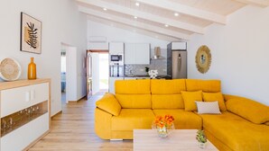 A modern living room with a yellow sofa, a wooden coffee table, and a kitchen in the background. - Cubo's Finca La Graciosa / private pool / free wifi (Alhaurin de la Torre)