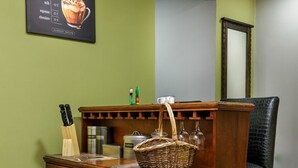 A wooden cabinet with drawers and a glass-fronted storage area, a wicker basket on top, and a framed menu on the wall.