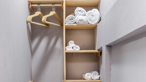A narrow walk-in closet with wooden shelves and a metal rod for hanging clothes.