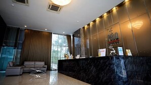 A modern hotel lobby with a reception desk, a large chandelier, and a seating area with a sofa and armchairs. - The Prio Condo (Chiang Mai)