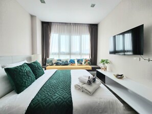 A modern hotel room with a large bed, a TV mounted on the wall, and a window with curtains. - The Prio Condo (Chiang Mai)