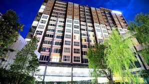 A multi-story hotel with a modern architectural design, featuring a series of balconies and large windows. - The Prio Condo (Chiang Mai)